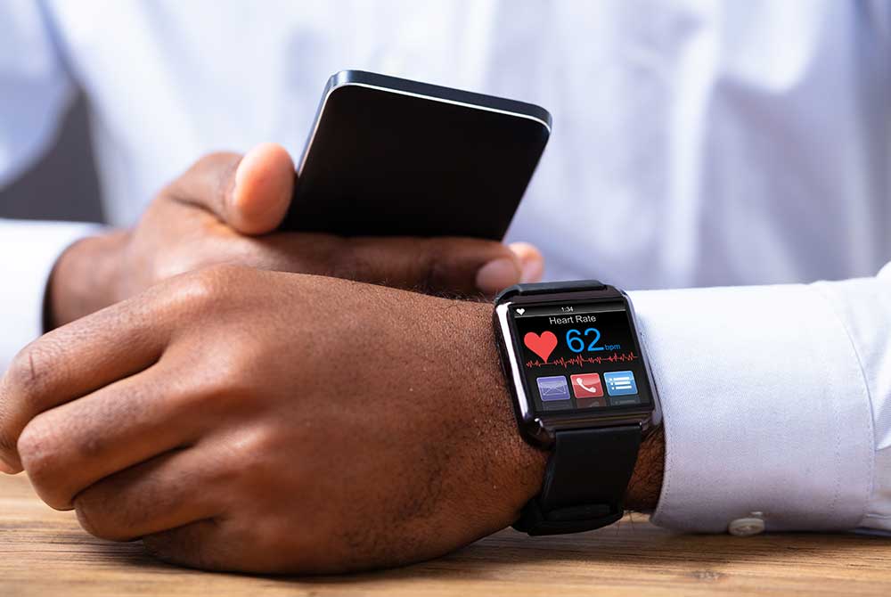 Person checking their heart rate on their smart watch while looking at their smart phone.